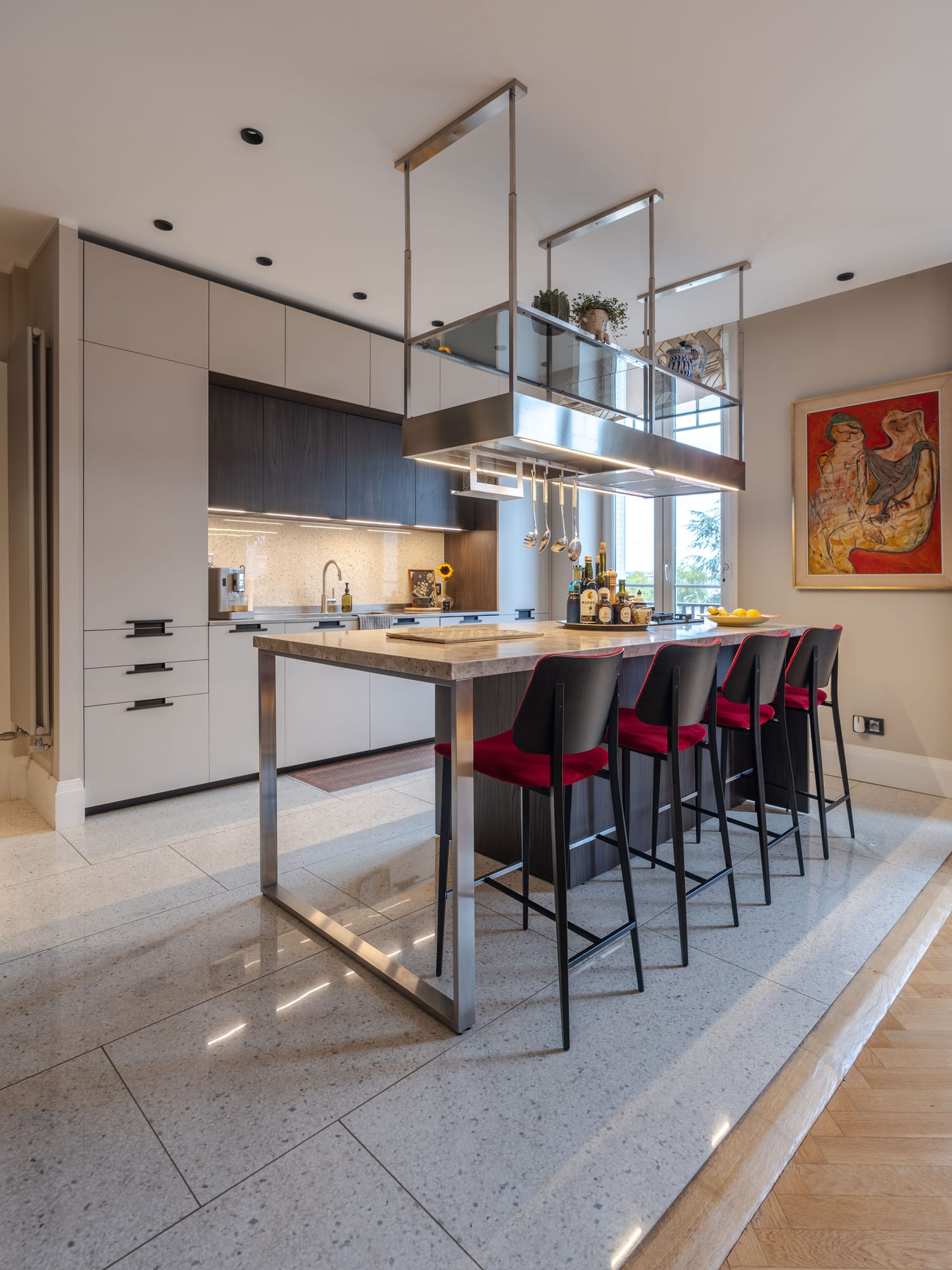 La cuisine ouverte vue depuis le séjour, la transition entre parquet et sol granito marquant les deux espaces