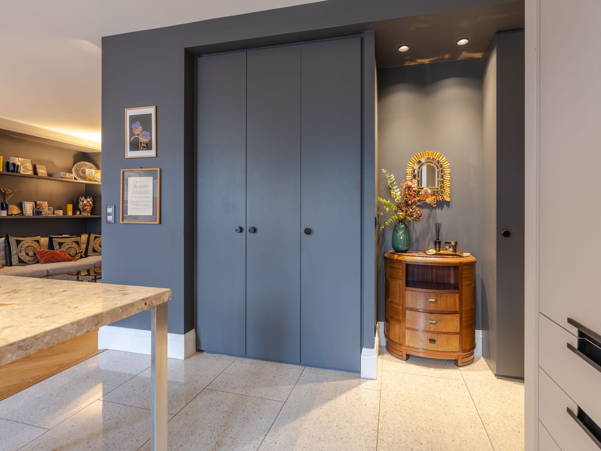 Rangements sur-mesure toute hauteur laqués gris à l’entrée, face à une commode Art déco