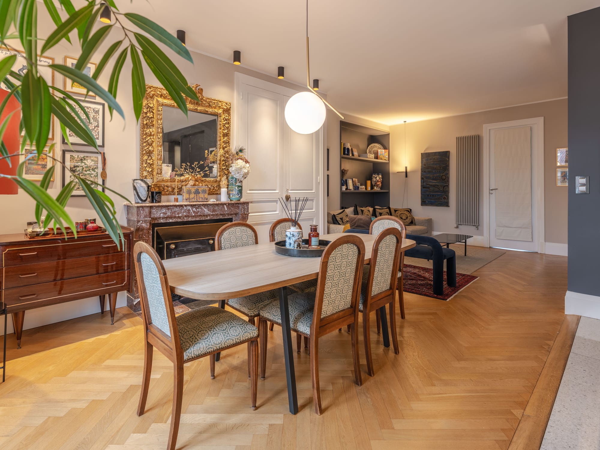 Salle à manger avec cheminée en marbre d’origine, miroir doré et parquet à chevrons restauré