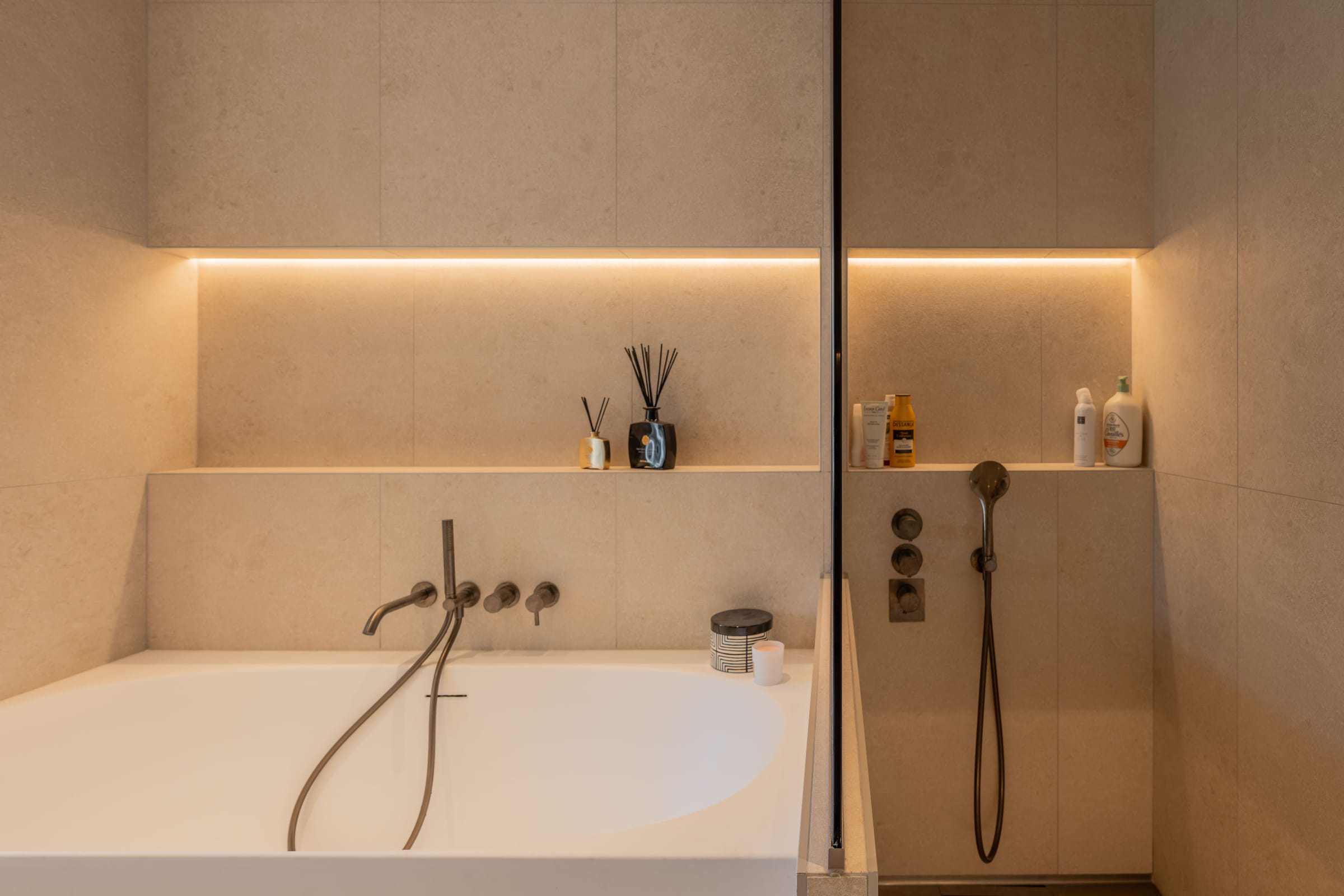 Niche de rangement rétroéclairée courant derrière la baignoire et se prolongeant dans la douche